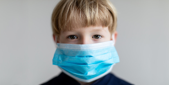Young boy wearing protective facial mask against covid-19
