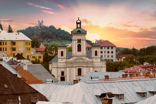 Old Slovakian mining town of Banska Stiavnica at dusk. The church of tthe Assumption of the virgin Mary is in front and calvary on the hill