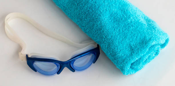 Pool towel and goggles on gray color surface. High angle view.
