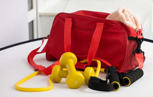 red bag, yellow dumbbells, expander , pink terry towel
