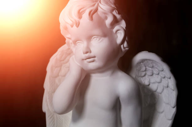 istock Beautiful white angel on black background close-up with flare 1216044555