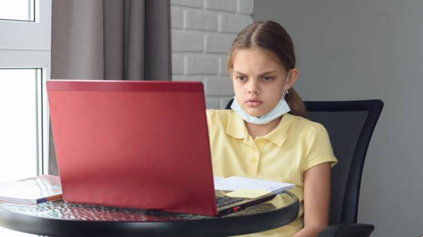 istock Girl in self-isolation mode sits at a computer and does homework online 1216044830