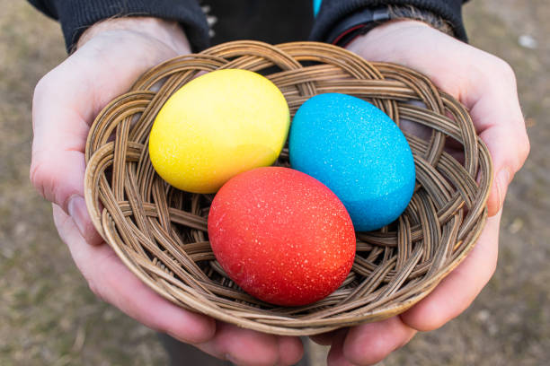 istock Three Easter colored plain eggs. A set of homemade eggs for Happy Easter holiday in a wicker basket. Man holding painted eggs 1216045839