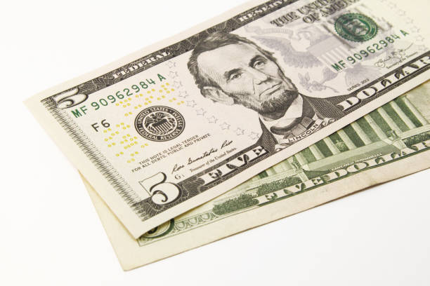 istock Five dollar bills in cash on white background 1216048232