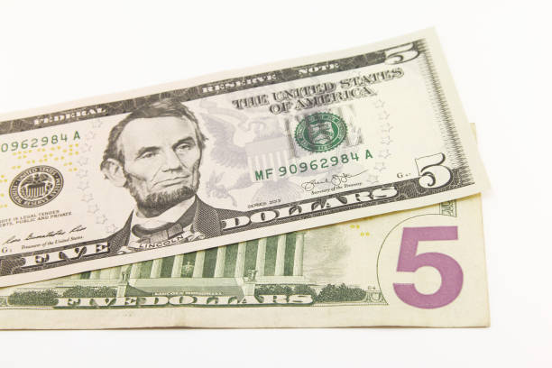 istock Five dollar bills in cash on white background 1216048471