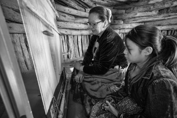 A Navajo Grandmother Teaching Her Young Granddaughter How To Weave On A Loom A Grandmother keeping the Navajo tradition alive for the younger generation by teaching her granddaughter how to weave hopi culture photos stock pictures, royalty-free photos & images