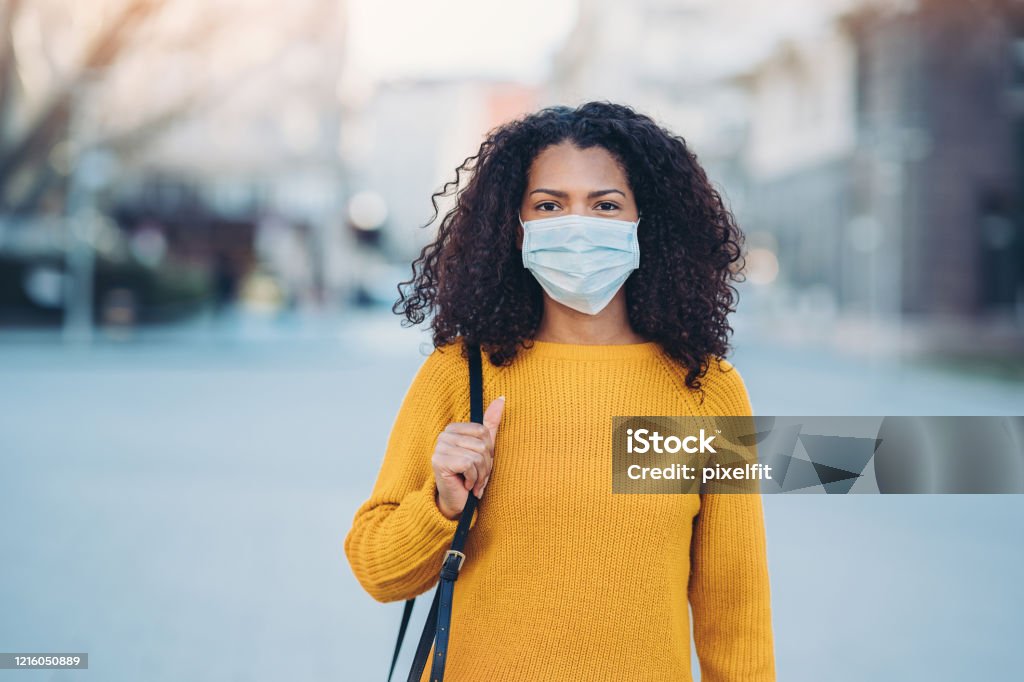 Young woman with a mask during pandemic Woman wearing a face mask walking outdoors Protective Face Mask Stock Photo