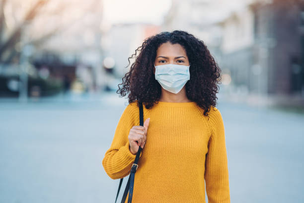 Young woman with a mask during pandemic Woman wearing a face mask walking outdoors commuter photos stock pictures, royalty-free photos & images