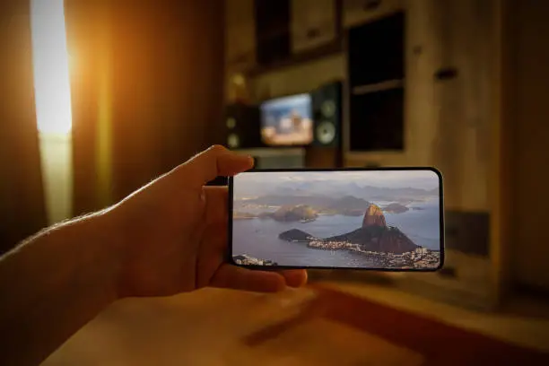 Concept of travel on a smartphone. Stay at home tourism. Online travel to Rio-De-Janeiro. Sugarloaf on a screen.