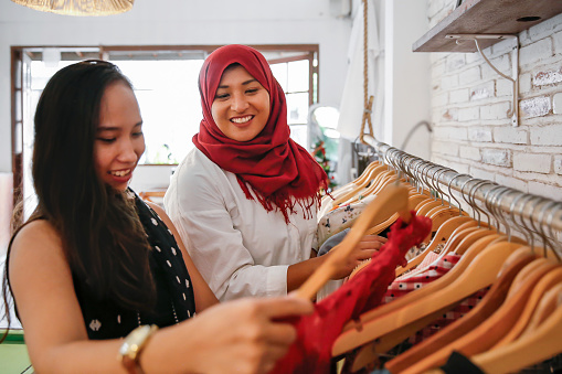 Close up two females Asian friends going shopping vintage clothes together in a thrift market