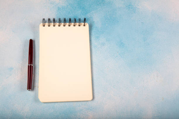 istock Small spiral notebook with fountain pen, isolated on white. 1216056548
