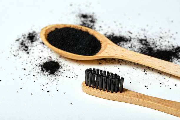 close up of eco bamboo toothbrush with black nylon bristles, black powder charcoal paste - exfoliating scrub imagens e fotografias de stock