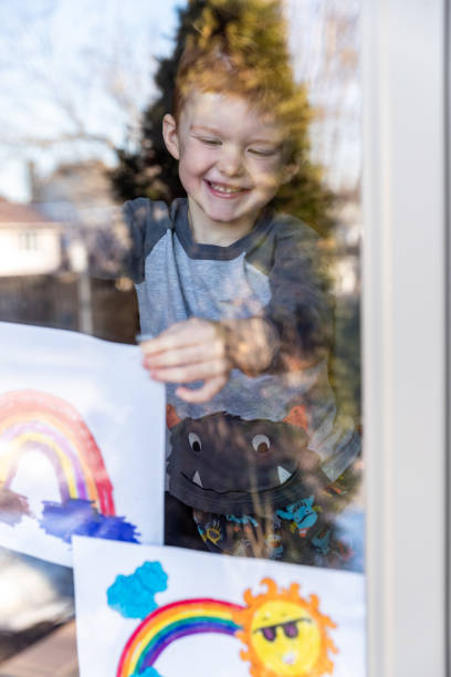 istock Young Boy sticking his drawing on home window during the Covid-19 crisis 1216065228