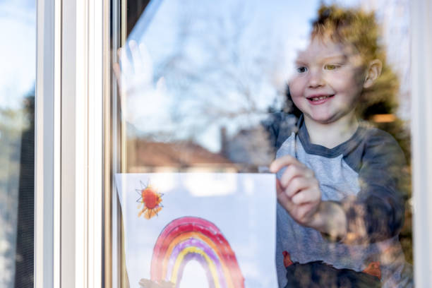 istock Young Boy sticking his drawing on home window during the Covid-19 crisis 1216065252