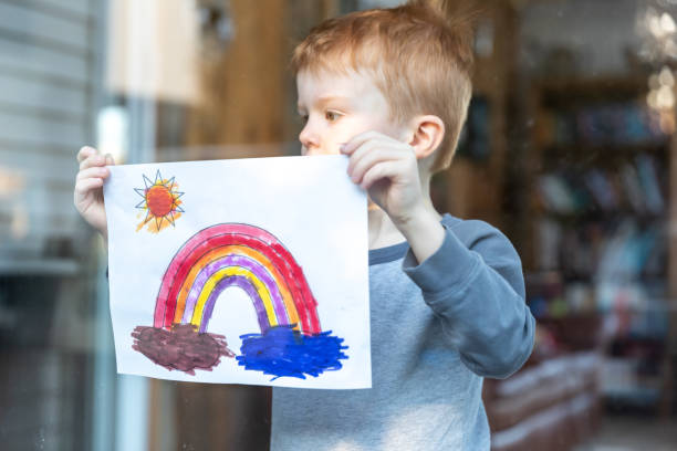 istock Young Boy sticking his drawing on home window during the Covid-19 crisis 1216065262