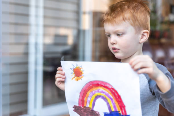 istock Young Boy sticking his drawing on home window during the Covid-19 crisis 1216065272