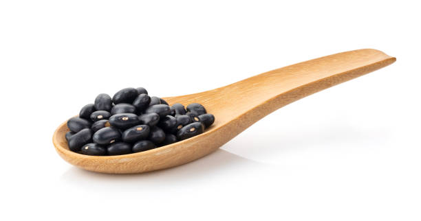 istock black beans in wood spoon isolated on white background 1216065303