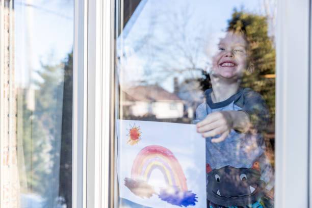 istock Young Boy sticking his drawing on home window during the Covid-19 crisis 1216065309