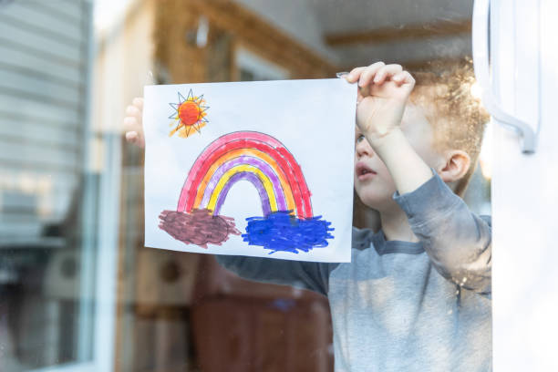istock Young Boy sticking his drawing on home window during the Covid-19 crisis 1216065345