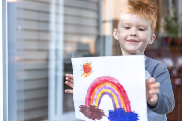 istock Young Boy sticking his drawing on home window during the Covid-19 crisis 1216065367