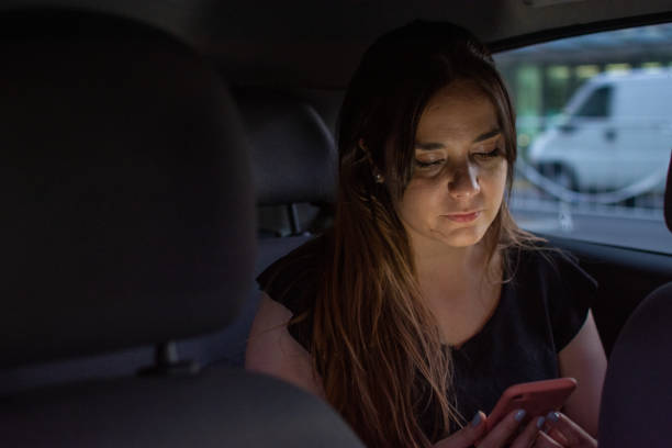 istock Reading a text message while on the back seat of the car 1216068287