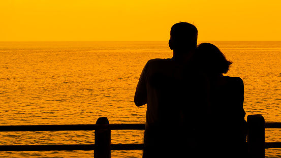 Silhouette of a back shot of couple, who enjoying the sea view at dawn