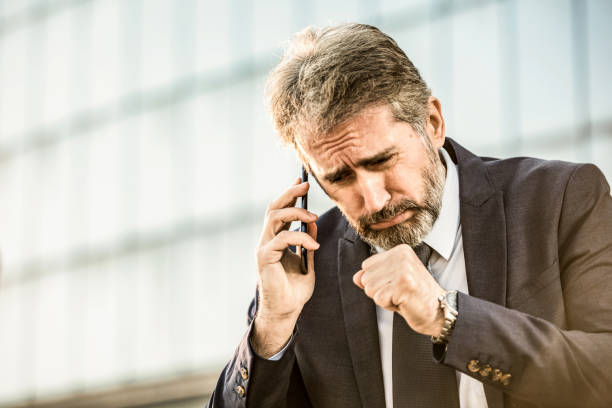 Mature businessman interrupting a phone call with coughing.