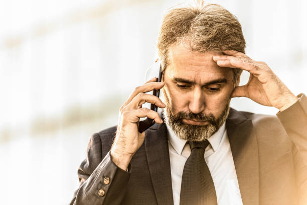 istock Overworked mature businessman talking on phone and having a headache. 1216070338
