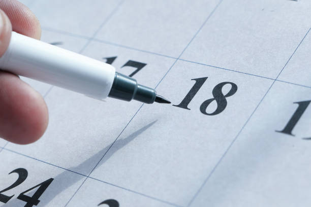 istock man's hand with pen marking on calendar, deadline concept 1216074597