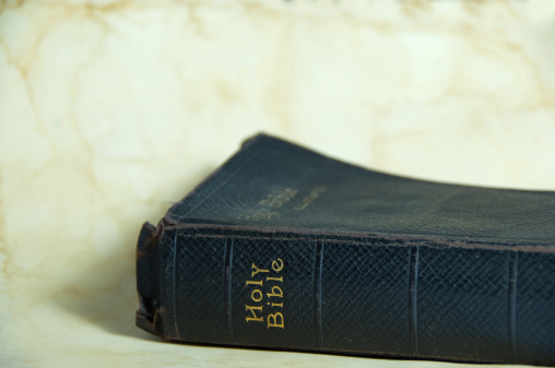 A old and worn leather covered Holy Bible on a grunge and waterstained parchment background. Copy space