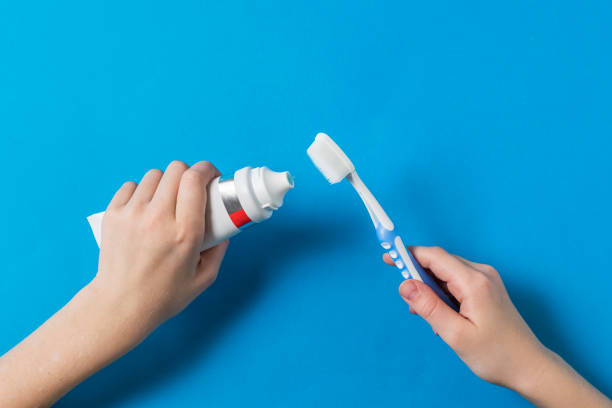 istock Baby's hands with a toothbrush with silicone bristles and toothpaste on a blue background. 1216086696