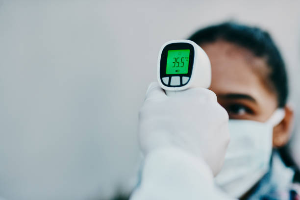 Cutting edge tech to help curb the spread Shot of a young woman getting her temperature taken with an infrared thermometer by a healthcare worker during an outbreak covid thermometer stock pictures, royalty-free photos & images