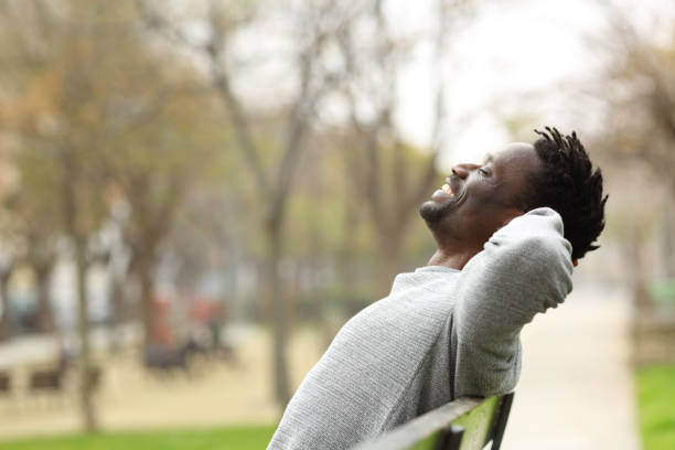 istock Happy black man relaxing on a bench in a park 1216086878