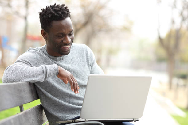 istock Happy black man using a laptop in a park 1216087037