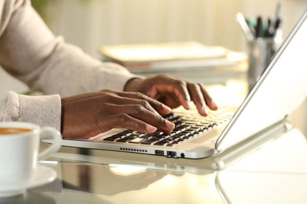 Black man hands typing on a laptop on a desk at home Close up of black man hands typing on a laptop on a desk at home entering data stock pictures, royalty-free photos & images