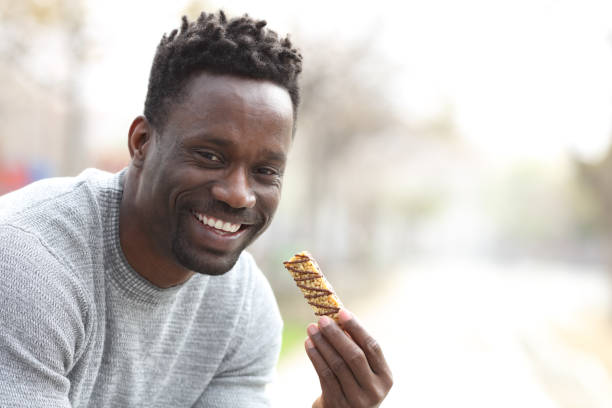 istock Happy black man holding granola bar looking at camera 1216087831