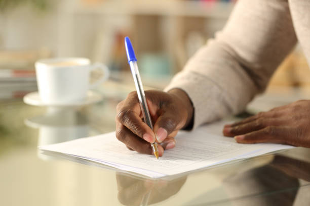 istock Black man hands filling out form on a desk 1216087852