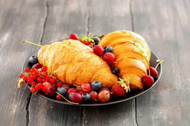 istock Delicious breakfast with fresh croissants and ripe berries on dark background. Selective focus. Copy space 1216088025