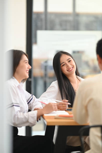 istock Photo of business developer team meeting/working/talking/discussing together while sitting at the wooden meeting table over modern office as background. 1216089803