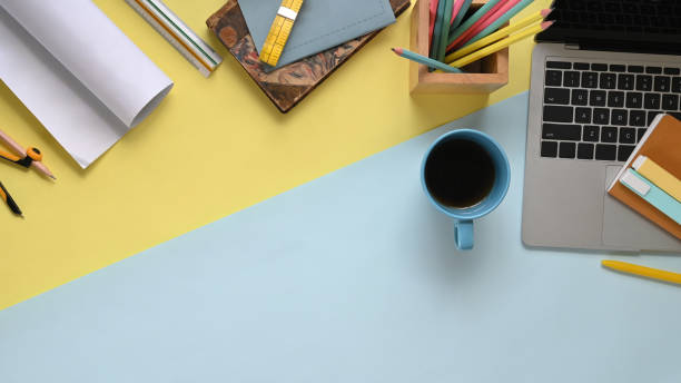 istock Top view image of two tones workplace that full of document, pencil compass, coffee cup, notebook, pencil holder, marker pens and computer laptop with black empty screen. 1216089815