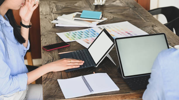 istock Cropped image of graphic designer team working together with computer tablet and color guide/information at the wooden meeting table over vintage office as background. 1216089823