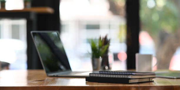 istock Home office work desk laptop putting on wooden working desk with stack of notebook, coffee cup and pencil holder over comfortable living room as background. 1216090098