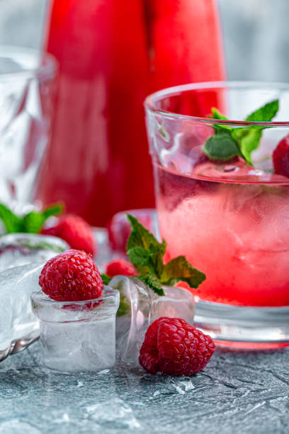 istock Raspberry cocktail, fizz, lemonade, ice tea with fresh mint on blue wooden background. Close up 1216092033