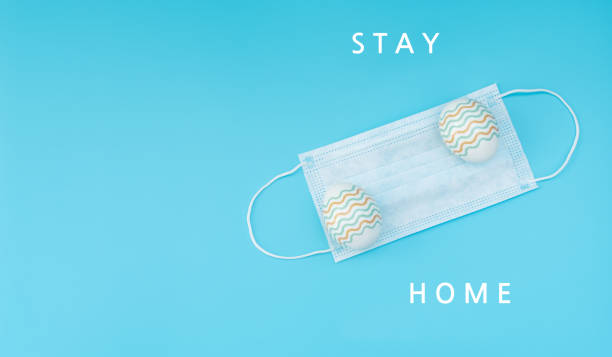 istock Decorated Easter eggs lie on the medical face mask on blue background with text. Happy Easter during quarantine concept. Biohazard, 2019-nCoV, COVID-19, social distance. Flat lay style with copy space 1216093219