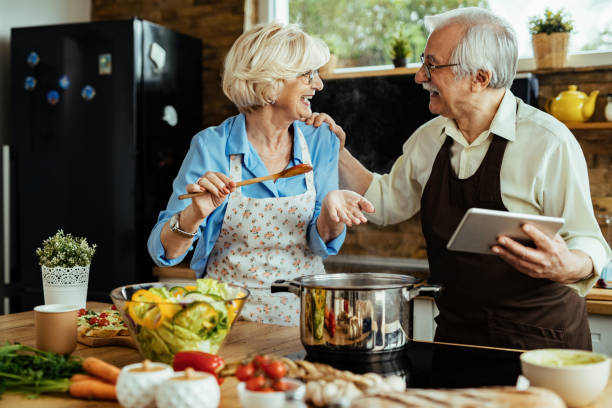 istock Happy mature couple having fun while cooking and using touchpad in the kitchen. 1216094652