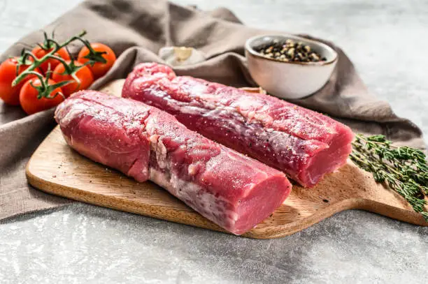Photo of Raw pork fillet tenderloin. Fresh meat. gray background. Top view