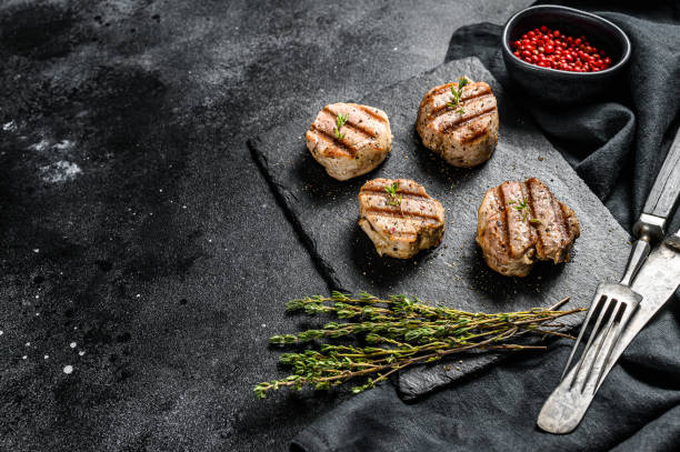 istock Tender boneless grilled pork chops. steak tenderloin. black background. Top view. Copy space 1216098195