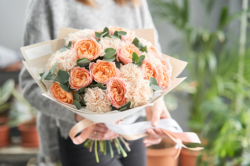 European floral shop. Beautiful bouquet of mixed flowers in womans hands. the work of the florist at a flower shop. Delivery fresh cut flower