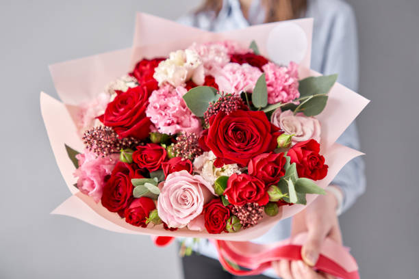 tienda de flores europea. hermoso ramo de flores mezcladas en manos de las mujeres. el trabajo de la floristería en una floristería. entrega flor fresca cortada. - multi colored flower red flower head fotografías e imágenes de stock