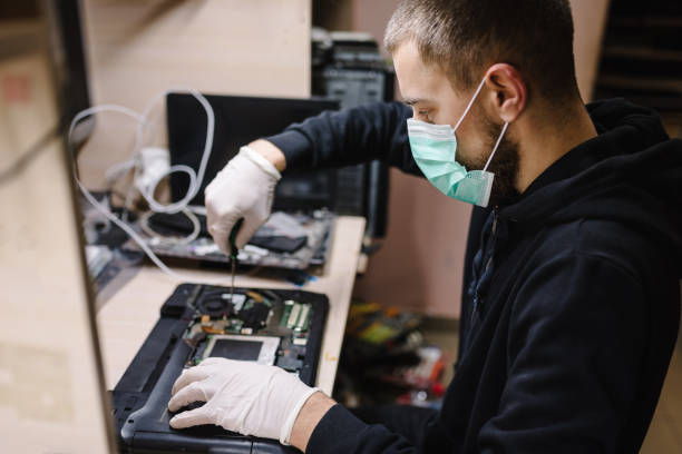 technician repairing a laptop in the lab. concept of repair computer, electronic, upgrade, technology.  coronavirus. man working, wearing protective mask in workshop. - cell human cell plant cell virus imagens e fotografias de stock